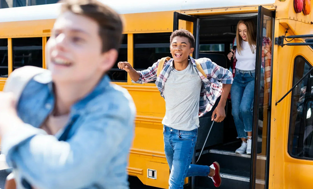 Teenagers taking off the school bus with happy faces